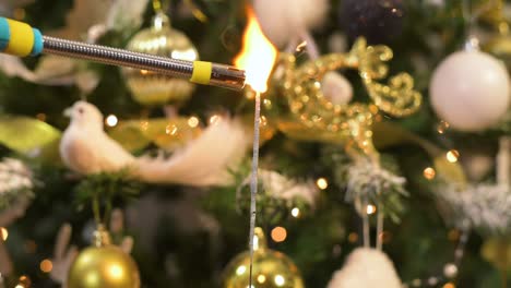 lighting up bengal sparkle fire in front of decorated christmas tree with white and gold ornaments. slow motion