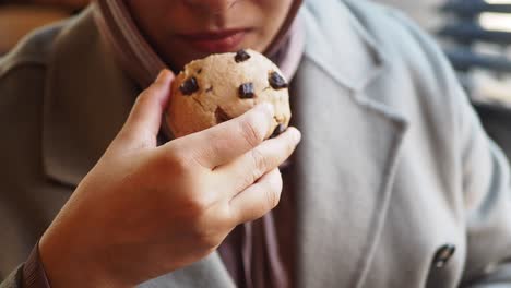 close-up of a woman holding a chocolate chip cookie