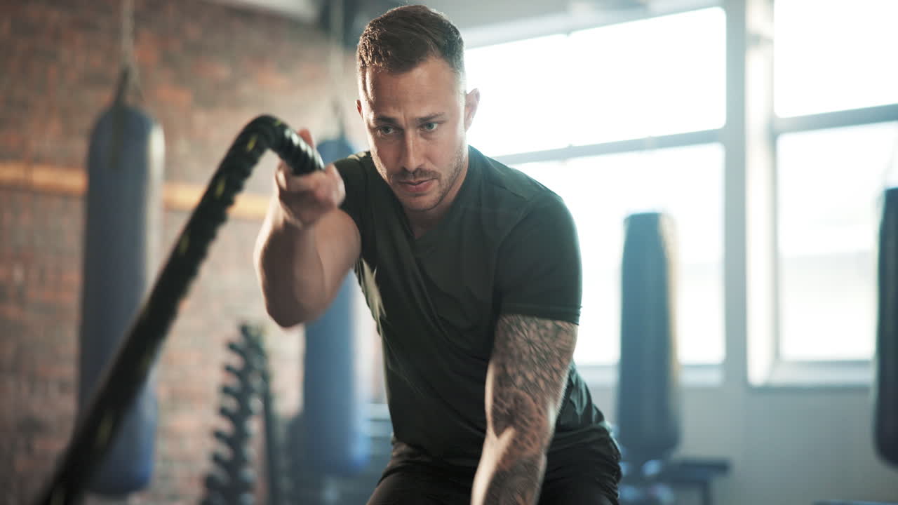 gimnasio, cuerda de batalla y hombre con ejercicio