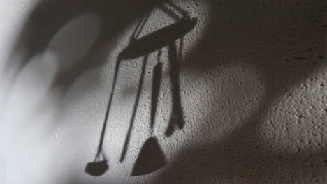 dynamic shadows of a wind chime on a textured wall
