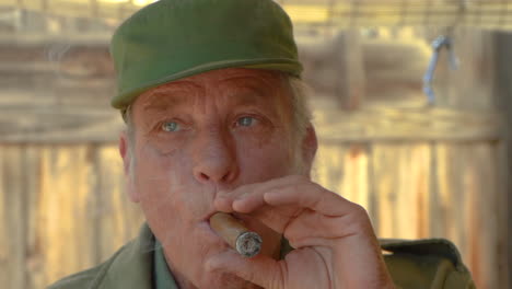 slow motion closeup of handsome man wearing a cap and smoking a cigar