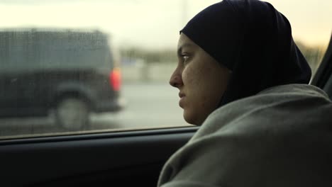 Junge-Muslimische-Frauen-Mit-Hijab,-Die-Während-Des-Sonnenuntergangs-Optimistisch-Aus-Dem-Nebligen-Autofenster-Schauen