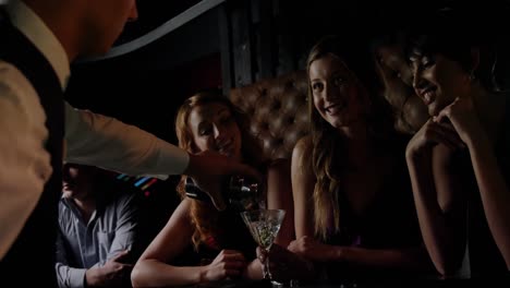 Waiter-pouring-cocktail-in-woman-glass-at-bar-counter