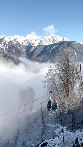 cable cars glide above a frosty forest with snow-covered mountains and clouds. gabala, azerbaijan