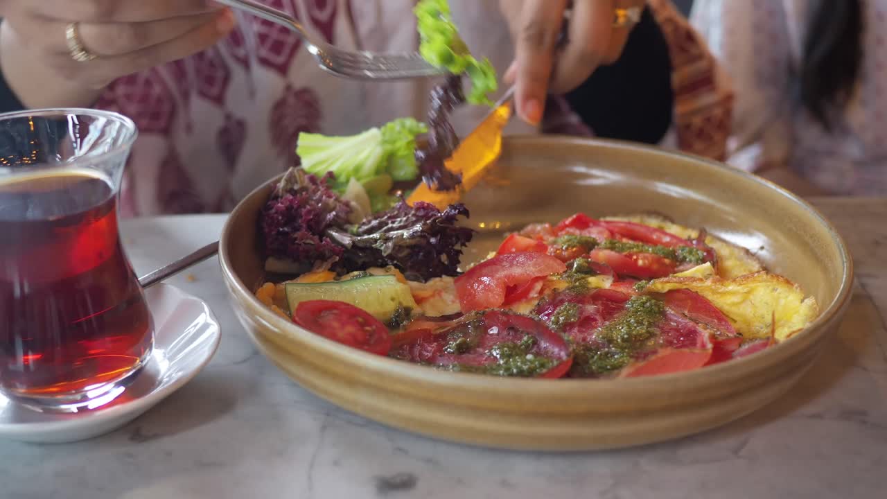Primo piano di persona che mangia una sana omelette con insalata e tè