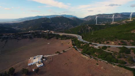 volando a través de parques eólicos en tarifa, españa al atardecer con montañas al fondo