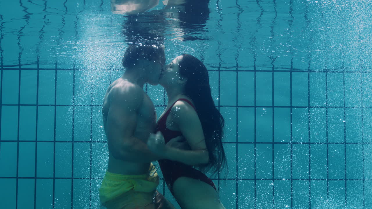 pareja romántica besándose bajo el agua en la piscina jóvenes enamorados disfrutando de un beso íntimo amantes sumergidos en el agua flotando con burbujas en una intimidad apasionada