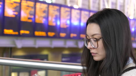 Woman-waiting-for-a-train-checks-her-phone-for-times-and-tickets-before-traveling