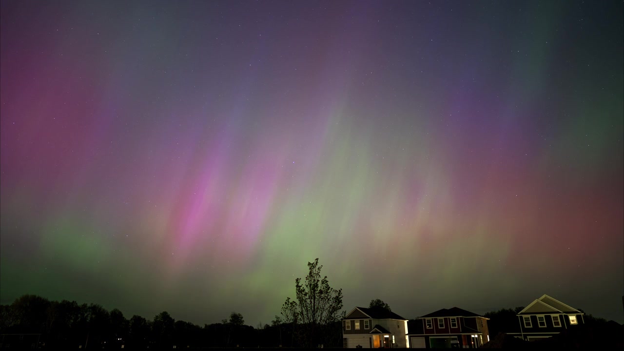 Aurore boreali colorate nel cielo notturno sopra case suburbane in Minnesota, USA.