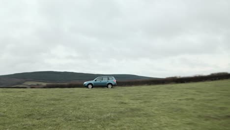 cinematic follow drone shot of farmer driving 4x4 around an empty field