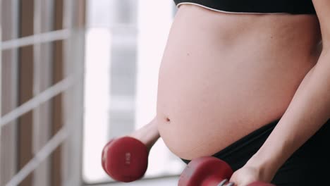 a pregnant woman in a sport costume is doing exercises