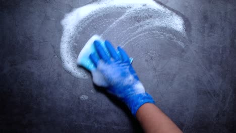 cleaning a dark gray countertop with soap and sponge