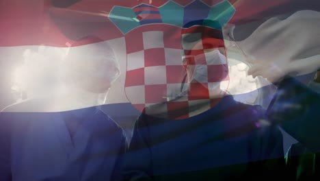 animation of waving croatia flag over team of diverse surgeons performing surgery at hospital