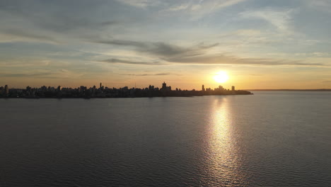 sunset establishing over posadas city skyline with calm river and glowing reflections