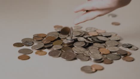 man dropping coins lightly onto a pile of change