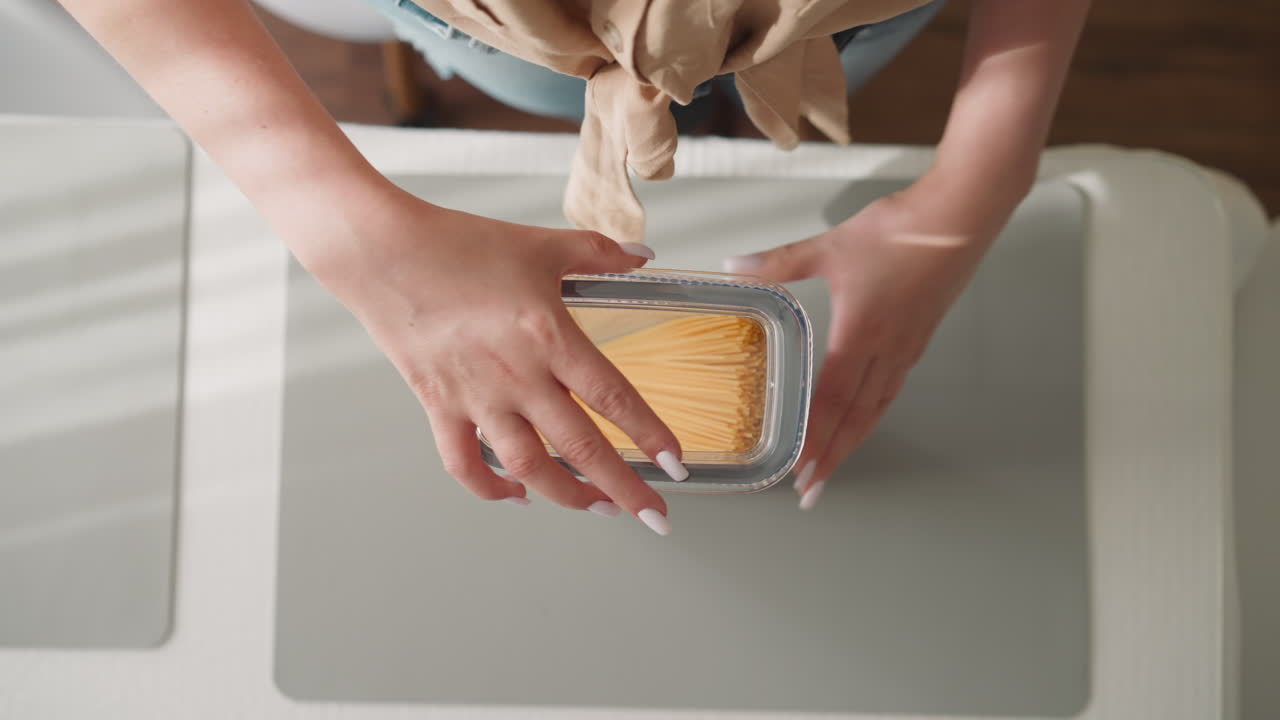 la ama de casa sacude el contenedor mirando el movimiento de los espaguetis