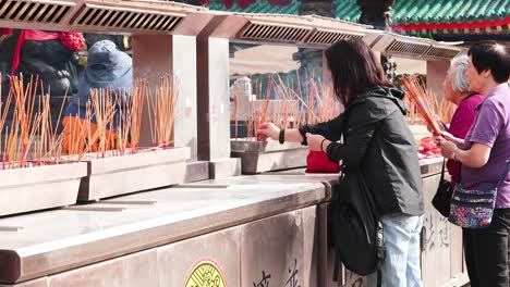 people lighting incense sticks at a temple