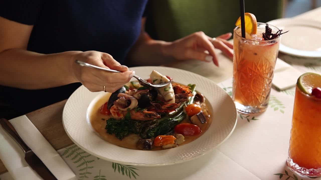 Woman Eating Delicious Seafood Dish with Fork in Restaurant