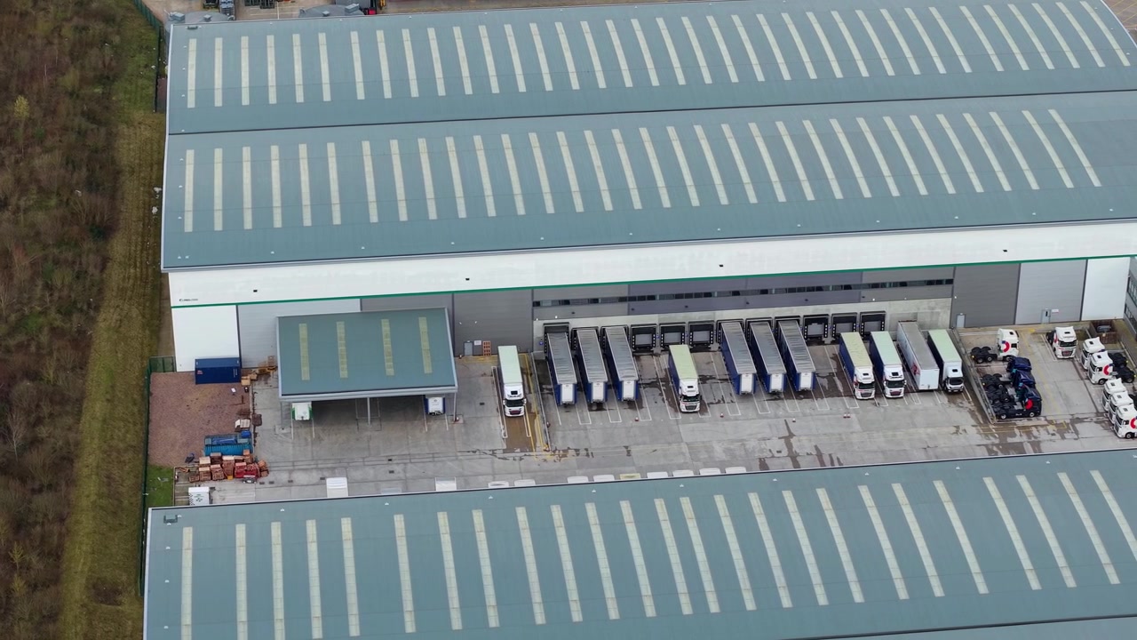 Veduta aerea di enormi e moderni magazzini di distribuzione con numerosi mezzi pesanti parcheggiati presso le baie di carico a Coleshill, Warwickshire, Regno Unito.