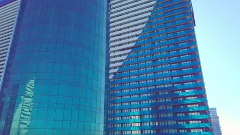 shot of reflections of sun, clouds and sky on glass windows of city skyscraper.