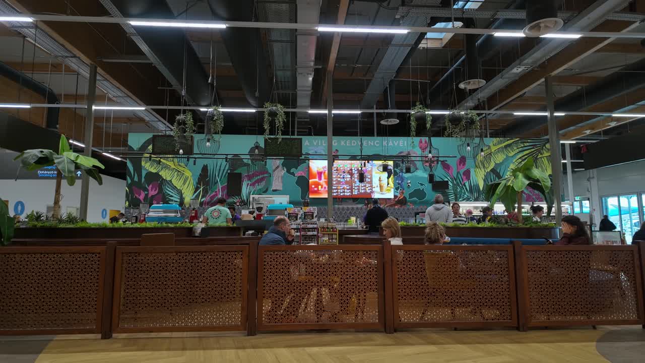Travelers relax at the Cafe Frei cafeteria, of which background design depicts the variety of favorite coffees from all over the world at the Liszt Ferenc Airport, Budapest, Hungary.