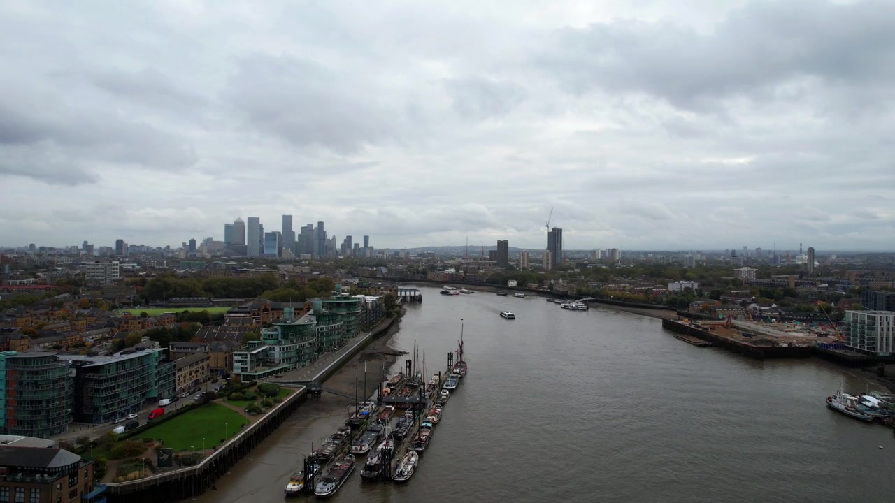 Zona industriale con barche ormeggiate lungo il fiume Tamigi e Canary Wharf sullo sfondo. Aerea
