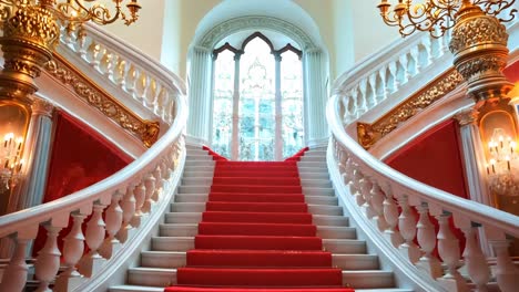 a red carpeted staircase in a building with chandeliers and chandelier