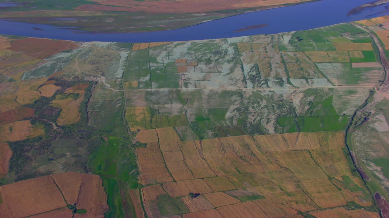 вид с воздуха на землю с фермами и голубую реку, дороги и деревья, раскинувшиеся на территории ферм