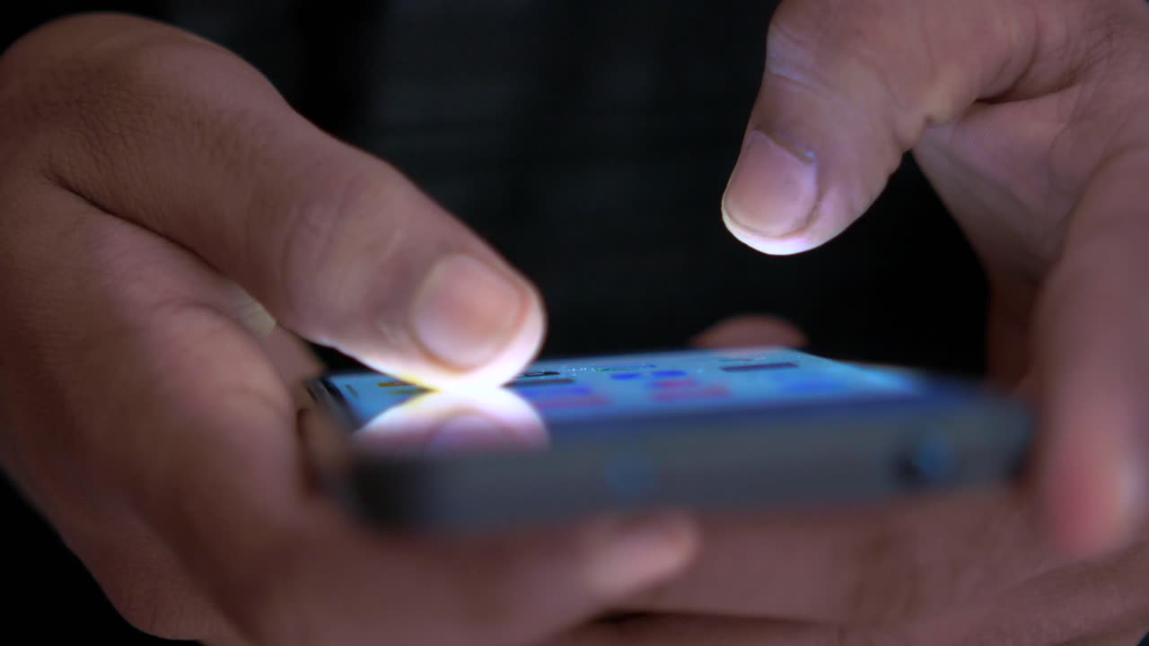 persona que utiliza un teléfono inteligente por la noche