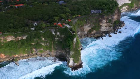 uluwatu temple, stone cliffs and ocean waves in bali, indonesia - drone shot