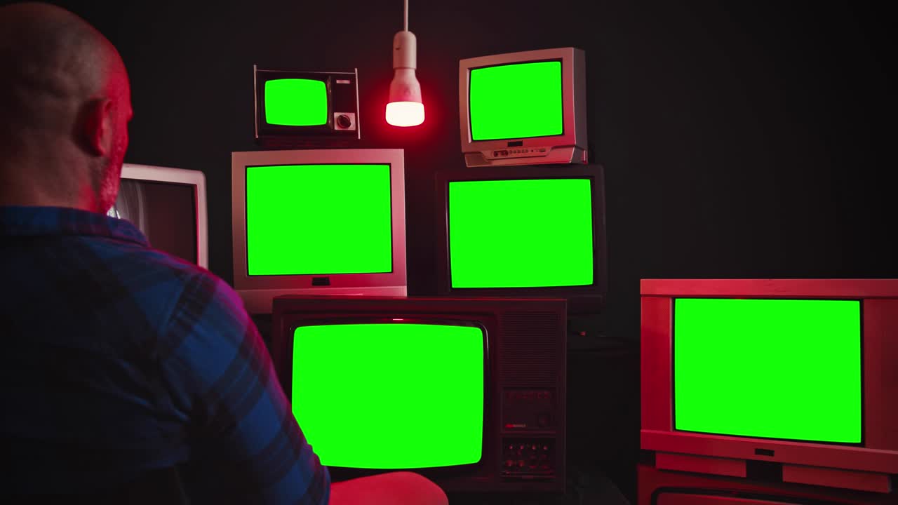 어두운 방에서 녹색 스크린으로 텔레비전을 보는 남자들. 뒷면.