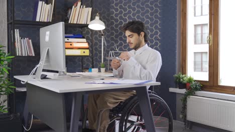 un trabajador discapacitado sentado en una silla de ruedas trabajando en la computadora.