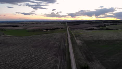vista aérea inclinada de una carretera rural con campos agrícolas alrededor al atardecer