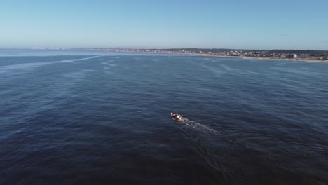 Aerial-view-of-fishing-boat-cruising-on-the-Atlantic-Ocean-along-the-uruguayan-coast-at-sunlight-and-blue-sky