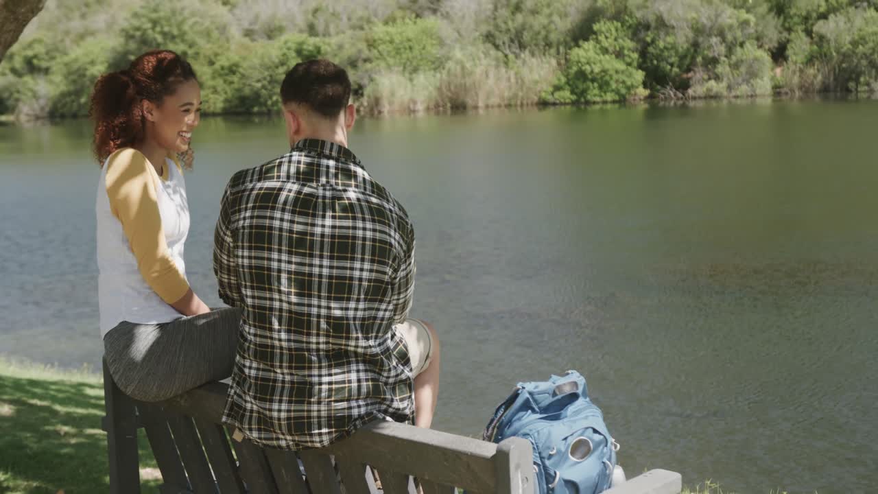행복 한 아프리카계 미국인 부부 가 숲 속 의 호수 의 벤치 에 앉아 있으며, 느린 움직임