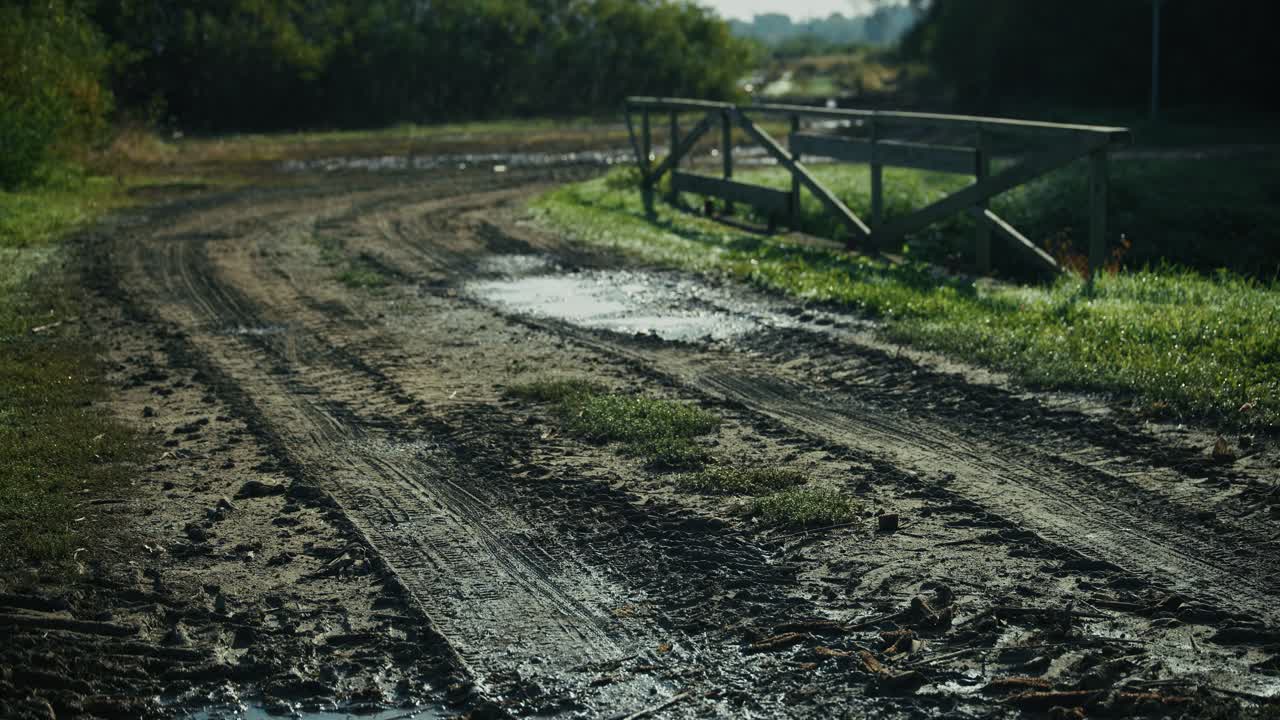 Muddy rural road with puddles and wooden fence in Lonjsko polje Krapje