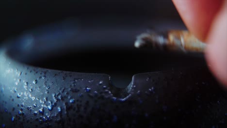 a macro close up shot of ash residue from a cigarette in a black stone ashtray, slow motion 4k video, white smoke 4