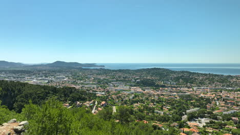 Die-Luftaufnahme-Der-Stadt-Toulon-Und-Des-Meeres-Zeigt-Sich-Zwischen-Den-Bäumen-Auf-Dem-Berg