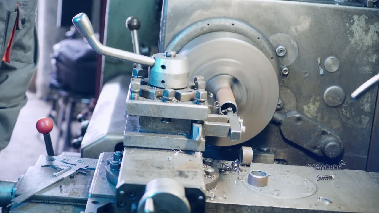 Close up hand heavy industrial worker is working on metal work factory process by performing mechanical turning operation at machine for steel structure industry