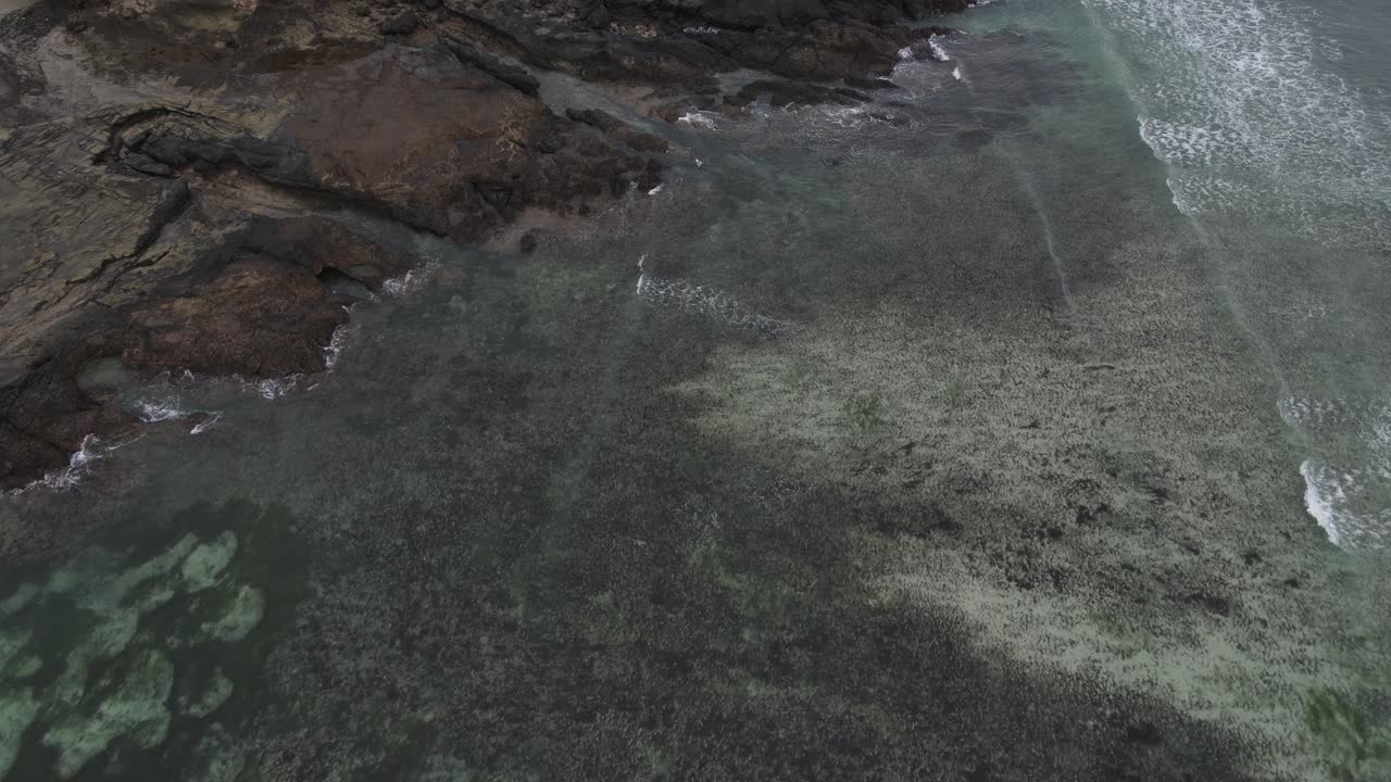 Aerial View of Ocean Waves Breaking on Rocky Coastline