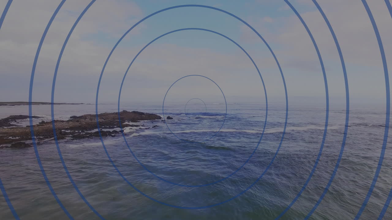 Concentric blue circles animation over ocean waves and rocky shoreline