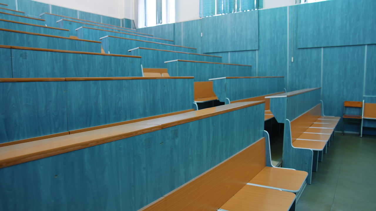 Empty lecture hall. Auditorium with wooden desks and chairs at educational center. Conference hall without students in the university.