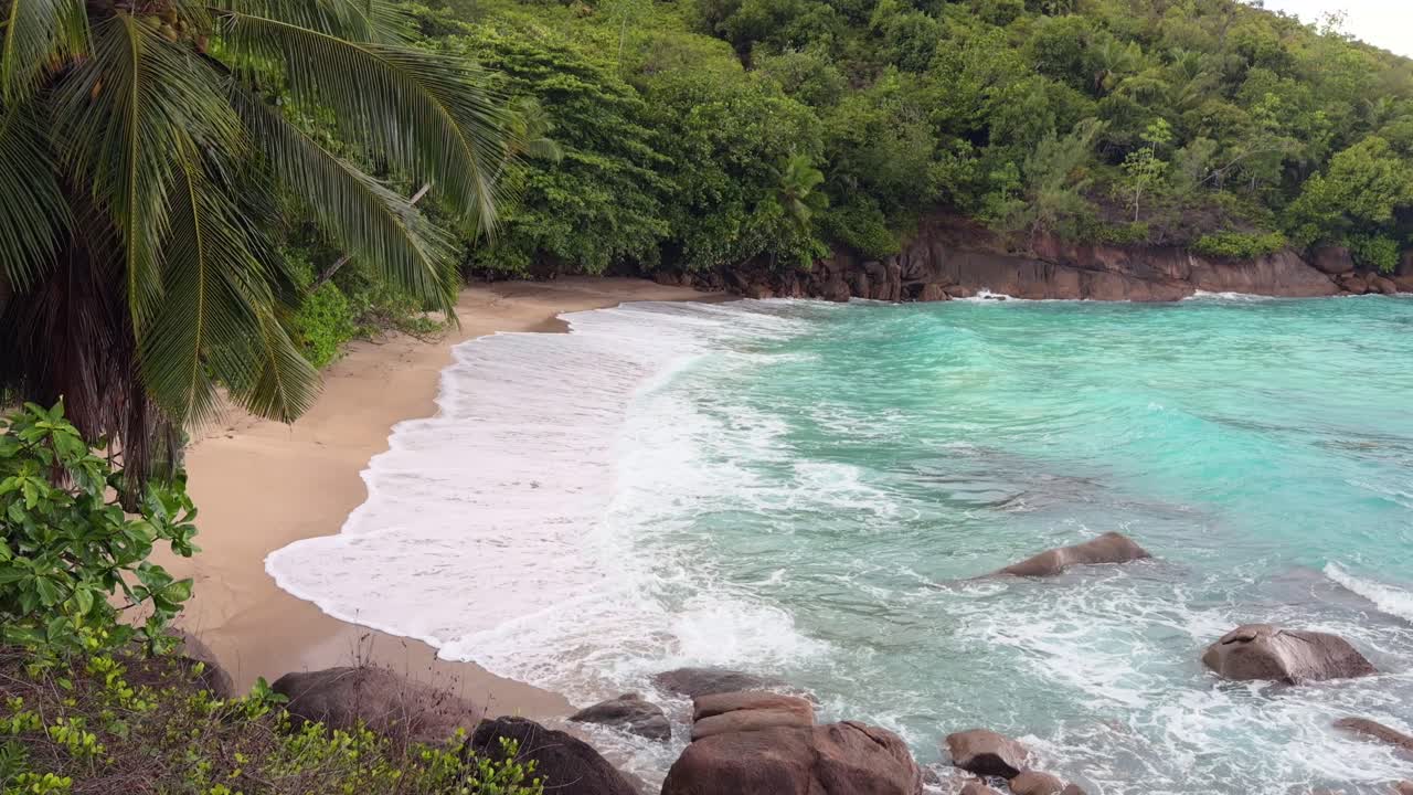 Anse, stor strand vid högvatten, vågor som slår mot vit sandstrand, frodig skog och granitstenar, Mahe, Seychellerna, 25fps