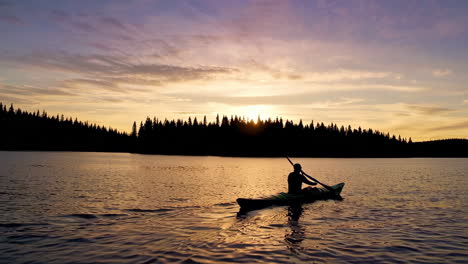 silhouette of a kayaker at sunset on a peaceful lake