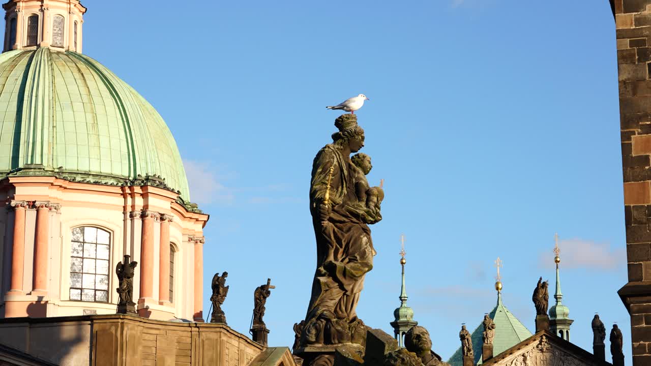 estatua de la virgen maría y el niño cristo en el puente charles y la cúpula verde de la iglesia