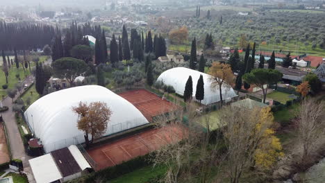 Panning-left-shot-above-tennis-courts-next-to-the-Arno-River-Match-Ball,-Vallina-Bagno-a-Ripoli-near-Florence-in-the-Tuscany-region-of-Italy