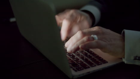 businessman typing on laptop keyboard in dark room