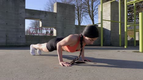 young lean woman doing pushups outdoors slider shot track left