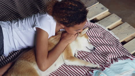 girl cuddling her dog on a bed