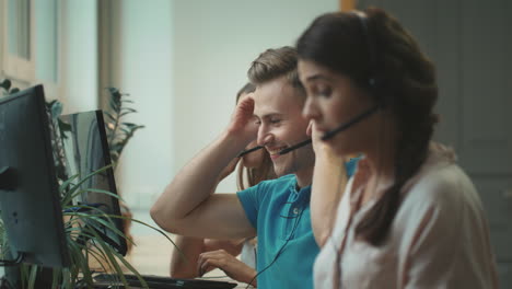 Young-operator-putting-headset-in-call-center.-Smiling-man-talking-with-client